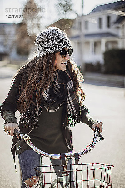 Junge Frau lacht beim Fahrradfahren durch ein Dorf im Herbst  Peaks Island  Maine  USA