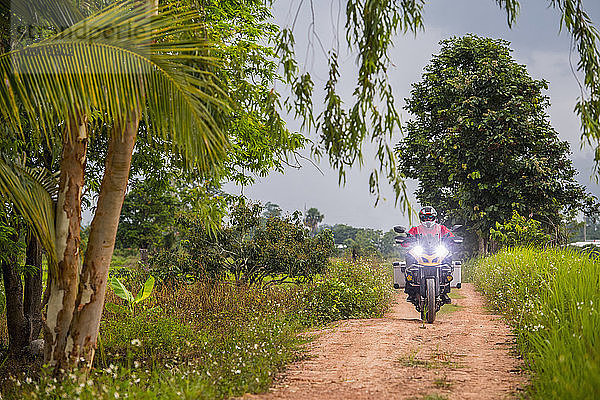Mann fährt auf einem Motorrad auf einer leeren unbefestigten Straße in Richtung Kamera  ¬ÝChiang¬ÝMai  ¬ÝMueang¬ÝChiang Mai District  Thailand