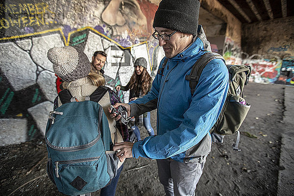 Freunde verteilen Stirnlampen vor einer mit Graffiti beschmierten Wand  bevor sie einen verlassenen Bunker erkunden  Portland  Maine  USA