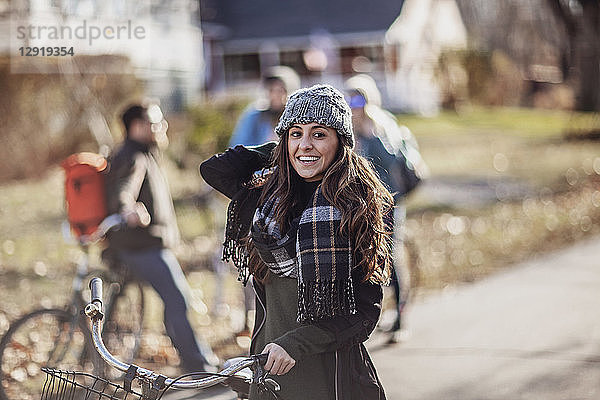 Porträt einer jungen Frau mit Schal und Strickmütze  die mit einem Fahrrad steht und in die Kamera lächelt  Portland  Maine  USA