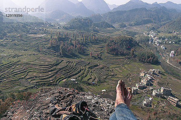 Blick auf die Füße eines Mannes  der auf dem Gipfel eines Berges sitzt  nachdem er ihn in Getu He  Provinz Guizhou  China  bestiegen hat