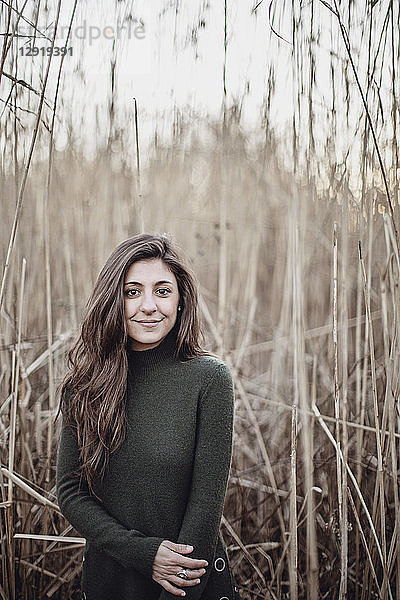 Lächelnde junge Frau steht vor langem Gras im Herbst  Peaks Island  Maine  USA