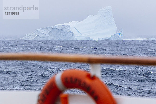 Ein Eisberg  gesehen von einem vorbeifahrenden Schiff in einem Sturm 12 Meilen vor der Küste der Westfjorde in Island