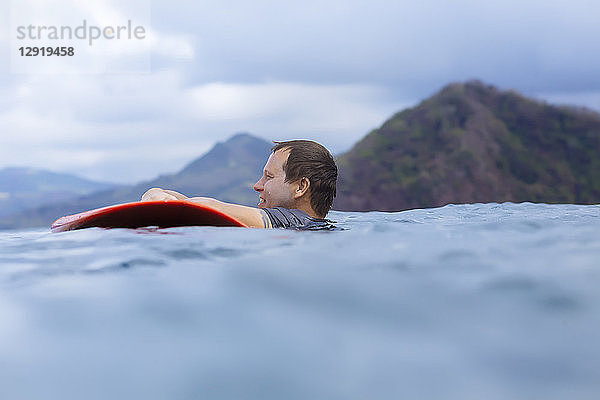 Seitenansicht eines Mannes mit Surfbrett im Meer
