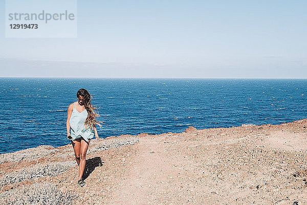 Frau  die tagsüber an einem flachen Küstenabschnitt mit dem Meer im Hintergrund spazieren geht  Teneriffa  Kanarische Inseln  Spanien