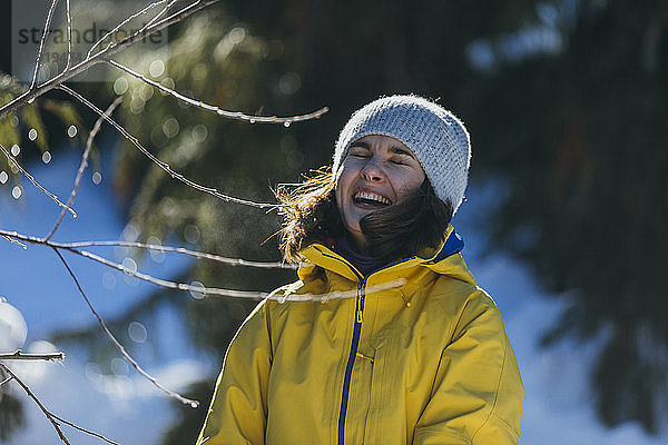 Taillenaufnahme einer Frau mit Strickmütze und Jacke  die im Winter im Freien lacht  Whistler  British Columbia  Kanada