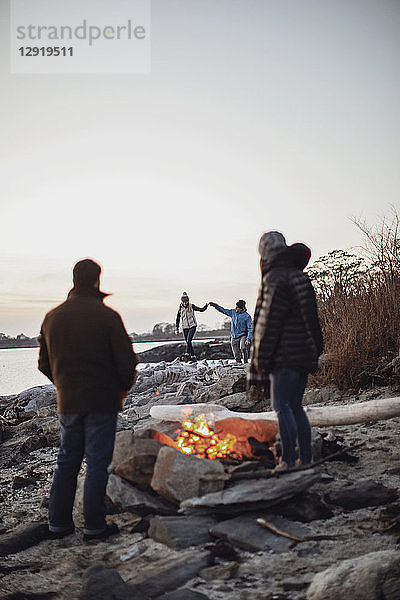 Eine Gruppe von Freunden genießt die Zeit am Lagerfeuer am Strand entlang der Küste  Peaks Island  Maine  USA