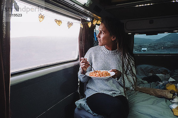 Stimmungsvolles Bild einer lateinamerikanischen Frau  die Nudeln im Wohnmobil isst  Teneriffa  Kanarische Inseln  Spanien