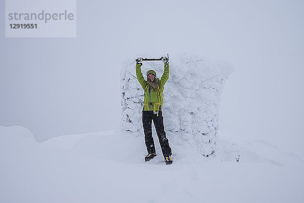 Frontalaufnahme einer Wanderin beim Feiern auf dem Gipfel des Matmora  Astvagoya  Lofoten  Norwegen