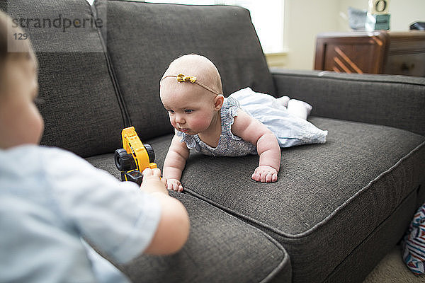 Bruder und Schwester spielen mit Spielzeug auf dem Sofa