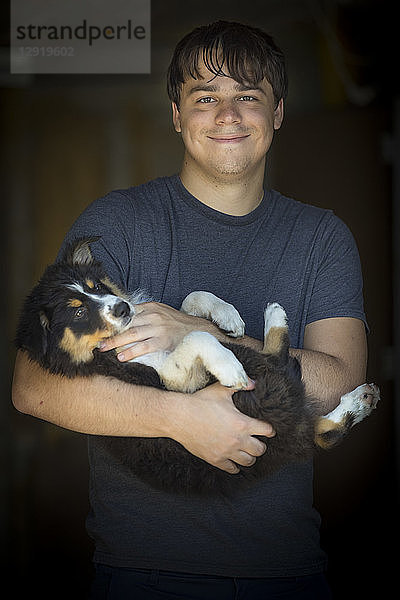 Porträt eines lächelnden Mannes  der einen Hund hält  in Taillenhöhe