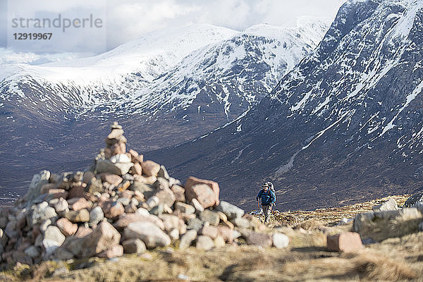 Ein Steinhaufen und ein Wanderer auf dem Gipfel der Devils Staircase beim Wandern auf dem West Highland Way in der Nähe von Glencoe in den schottischen Highlands  Schottland  Vereinigtes Königreich
