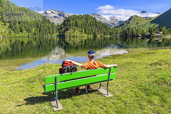 Wanderer mit Rucksack ruht sich auf einer Bank aus  Cavloc-See  Forno-Tal  Maloja-Pass  Engadin  Graubünden  Schweiz  Europa