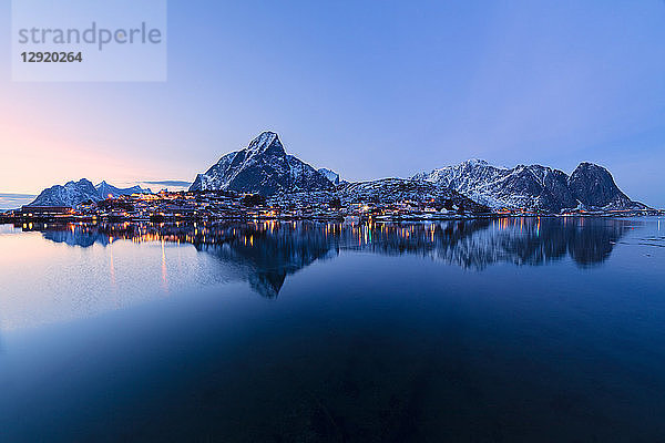 Überblick über das Dorf und die schneebedeckten Gipfel in der Abenddämmerung  Reine Bay  Lofoten-Inseln  Nordland  Norwegen