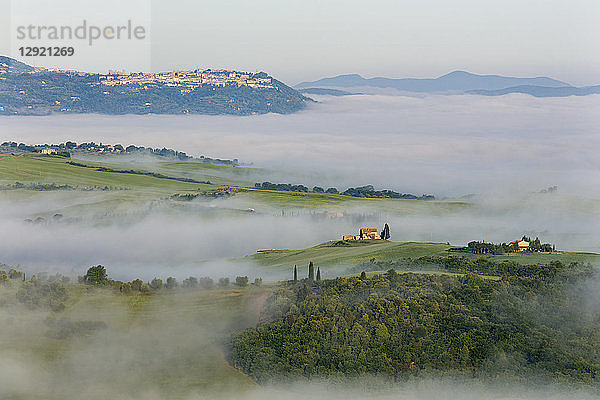 Blick über das Val d'Orcia auf Montalcino  das auf einem Hügel über den Wolken und dem Nebel im Tal liegt  UNESCO-Weltkulturerbe  Toskana  Italien  Europa