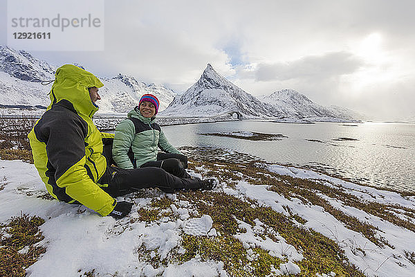 Wanderer auf schneebedeckten Wiesen mit Volanstinden im Hintergrund  Fredvang  Lofoten  Nordland  Norwegen