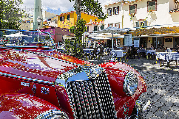 Blick auf einen roten MG-Oldtimer vor einem traditionellen Al Fresco-Restaurant in der Altstadt  Funchal  Madeira  Portugal