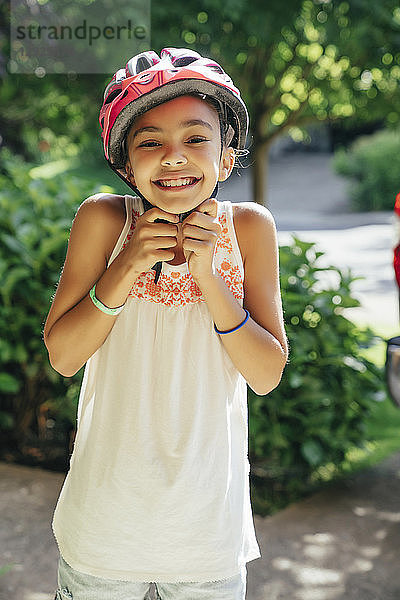 Lächelndes Mädchen setzt Fahrradhelm auf