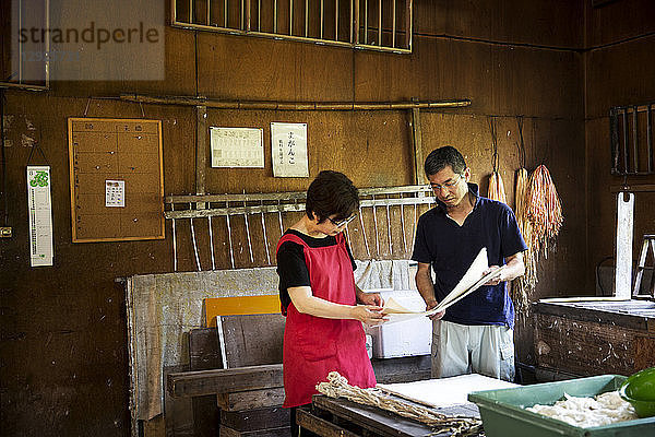 Japanischer Mann und Frau  Handwerker  die in einer traditionellen Werkstatt Washi-Papier herstellen.