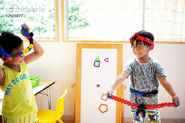 Zwei lächelnde Kinder spielen in einer japanischen Vorschule mit Spielzeug.