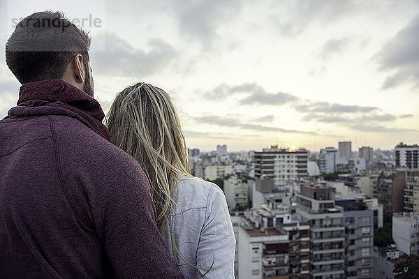 Paar steht auf einer Terrasse und schaut auf die Stadtlandschaft