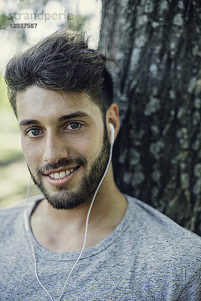 Nahaufnahme eines lächelnden jungen Mannes beim Hören von Musik