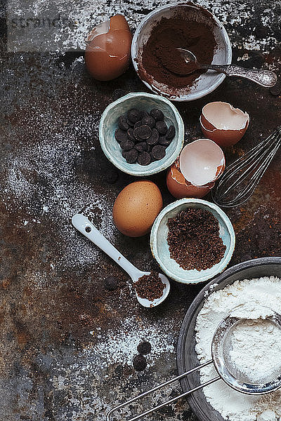 Ein Arrangement von Backutensilien: Kakao  Schokoladenstückchen  Eier  Mehl und Zucker