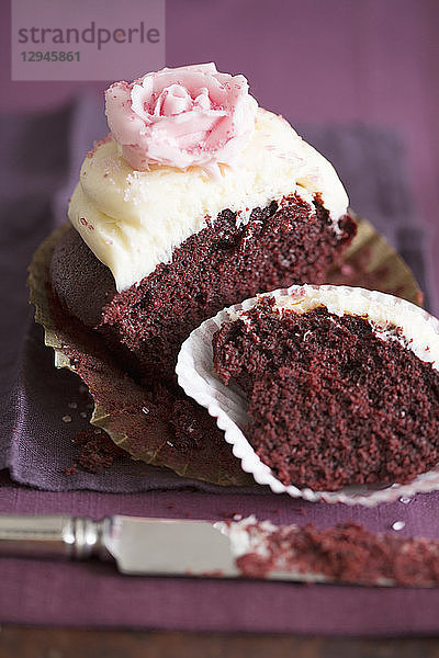 Ein halber Schokoladen-Cupcake mit Vanillecreme und einer Zuckerrose