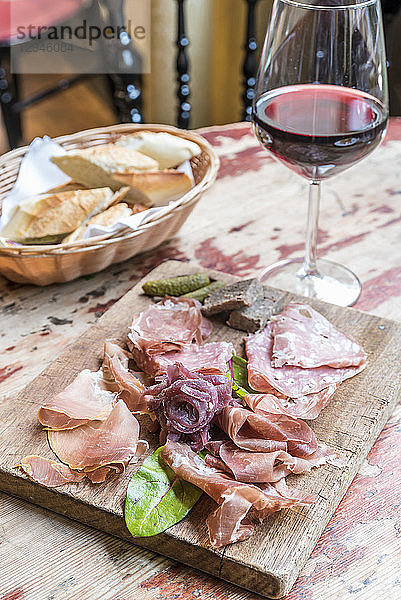 Tafel mit Aufschnitt und Wurstwaren  Salami  Prosciutto mit Brot im Hintergrund