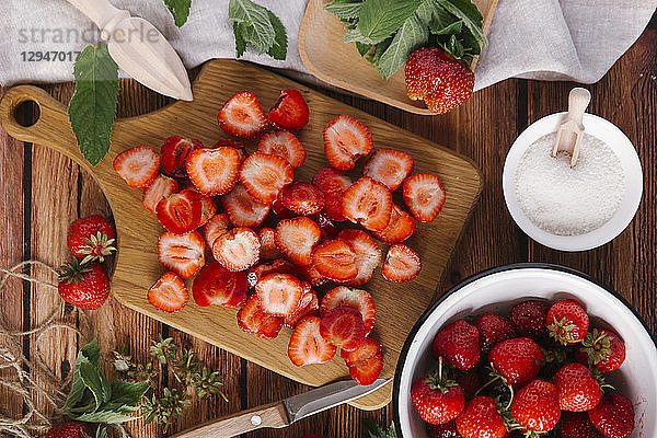 Frische Erdbeeren  geputzt und in Scheiben geschnitten  und eine Schale mit Zucker