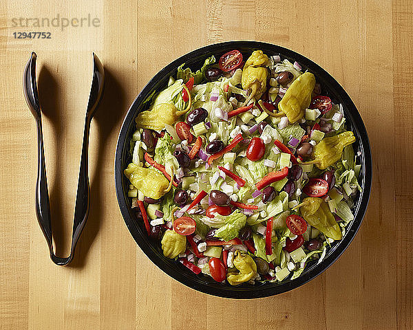Griechischer Salat mit Plastikzange  aufgenommen auf einem Metzgerblocktisch von oben