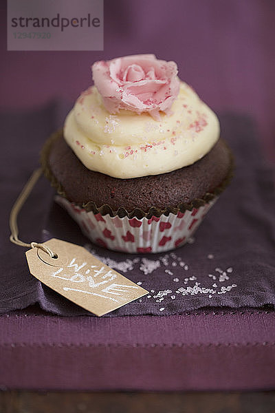 Ein Schokoladen-Cupcake mit Vanillecreme und einer Zuckerrose