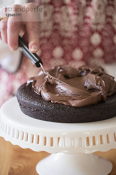 Eine Torte wird gebacken: Schokoladencreme wird auf einen Tortenboden gestrichen