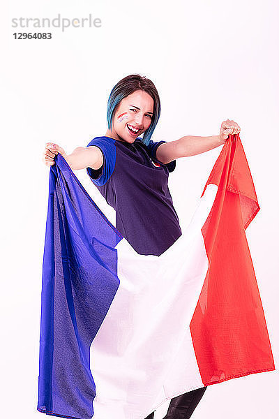 Porträt einer jungen Anhängerin der französischen Fußballmannschaft mit der Nationalflagge in der Hand