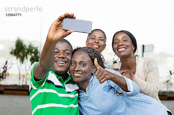Gruppe junger Menschen  die ein Foto mit einem Mobiltelefon machen  um ihr Wiedersehen zu feiern.