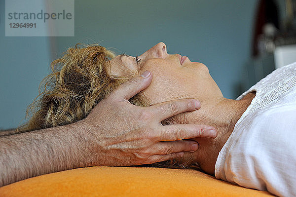 Frankreich  Person in der Praxis eines Osteopathen  Frau in chiropraktischer Behandlung  Gesichtsmassage.