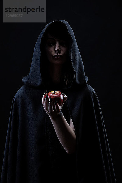 Porträt einer Hexe  die einen Apfel in der Hand hält