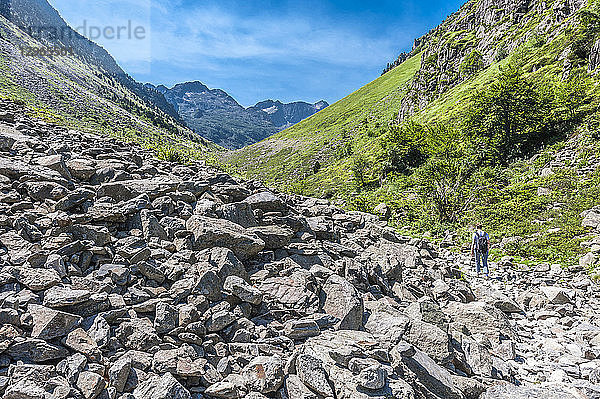 Frankreich  Pyrenäen-Nationalpark  Region Okzitanien  Val d'Azun  Haute-vallee d'Estaing  Wanderer auf einem Weg durch eine Masse von umgestürzten Felsen