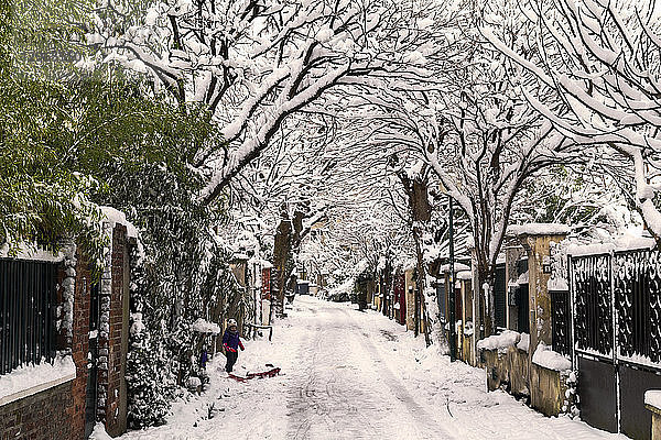 rance  Pre-Saint-Gervais  Eine Straße im Wohngebiet unter dem Schnee. Ein Mädchen und ihr Schlitten.