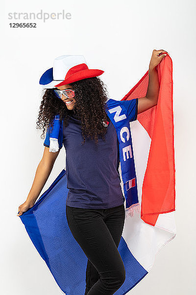Porträt eines jungen Anhängers der französischen Fußballmannschaft  der einen Hut  eine Trikolore-Brille und eine Fahne seiner Mannschaft trägt