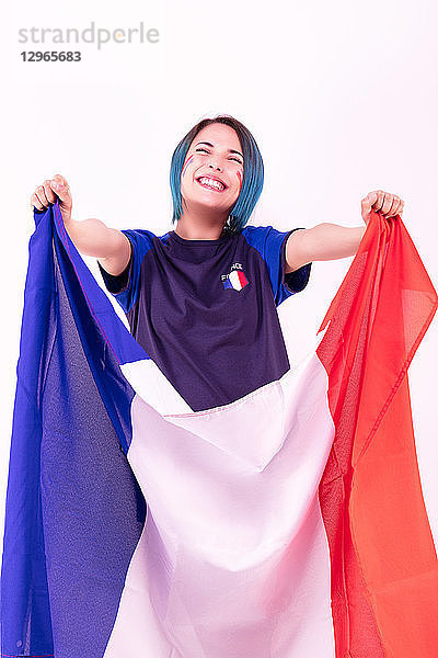 Porträt einer jungen Anhängerin der französischen Fußballmannschaft mit der Nationalflagge in der Hand