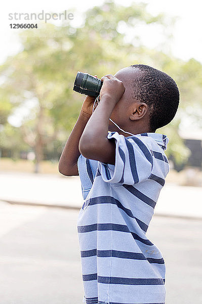 Kind schaut durch das Fernglas  um sein Ziel zu suchen.