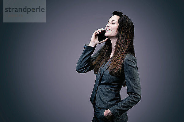 Porträt einer jungen lächelnden Geschäftsfrau am Telefon