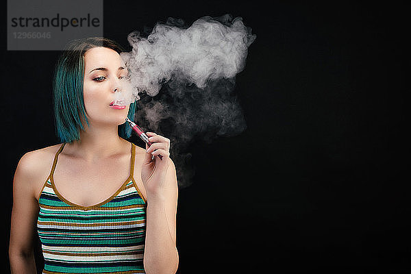 Junge Frau dampft eine elektronische Zigarette