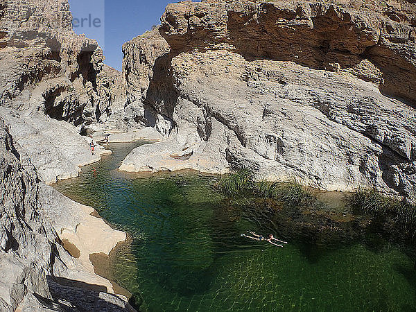 OMAN  Wadi Bani Khalid  eine Gruppe europäischer Touristen schwimmt im grünen Wasser einer Schlucht