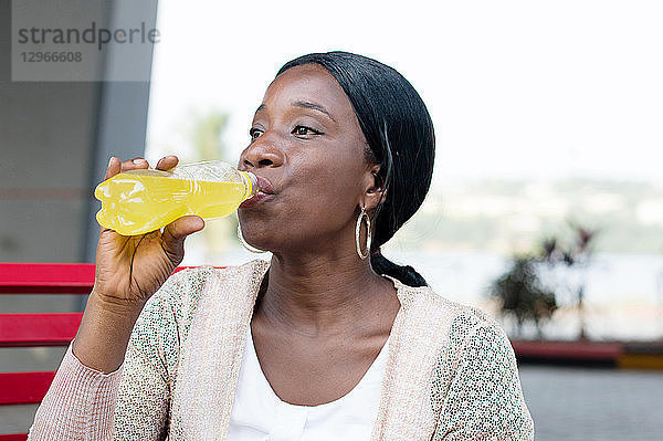 Frau trinkt eine Limonade aus der Flasche