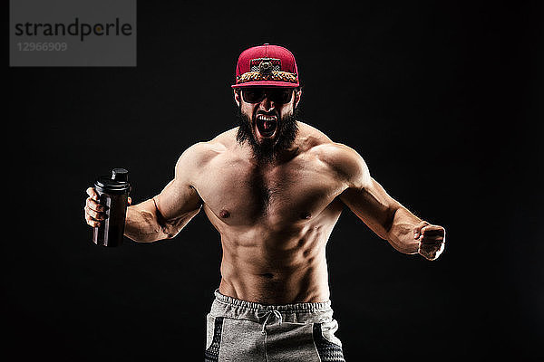 Ein schreiender Bodybuilder mit einem Proteinshaker in der Hand