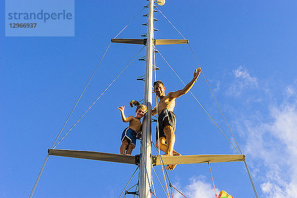 Ein Vater und sein Sohn auf dem Mast eines Segelbootes vor blauem Himmel  Hog Island  Grenada  Kleine Antillen  Westindien
