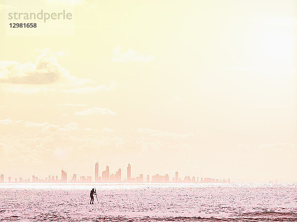 Silhouette des Mannes Paddleboarding auf dem Meer bei Sonnenuntergang