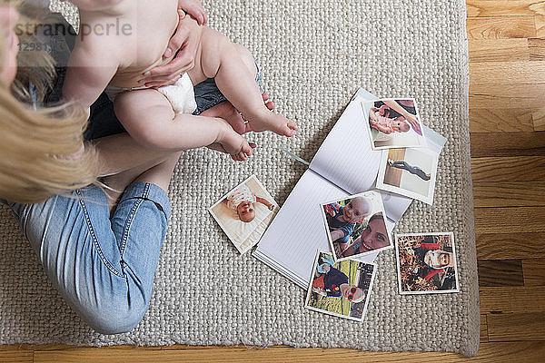 Fotografien und Buch von Mutter und Tochter auf einem Teppich sitzend